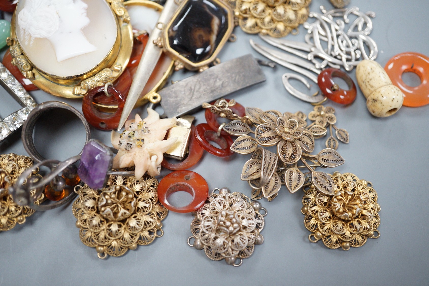 Assorted jewellery including jade pendant, yellow metal buckle brooch, modern silver hinged bangle, cameos, unmounted oval moonstone, agate set white metal buckle brooch, 800 standard paper knife etc.